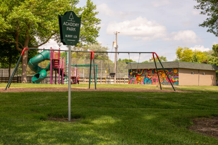 A grassy park area with a sign reading 