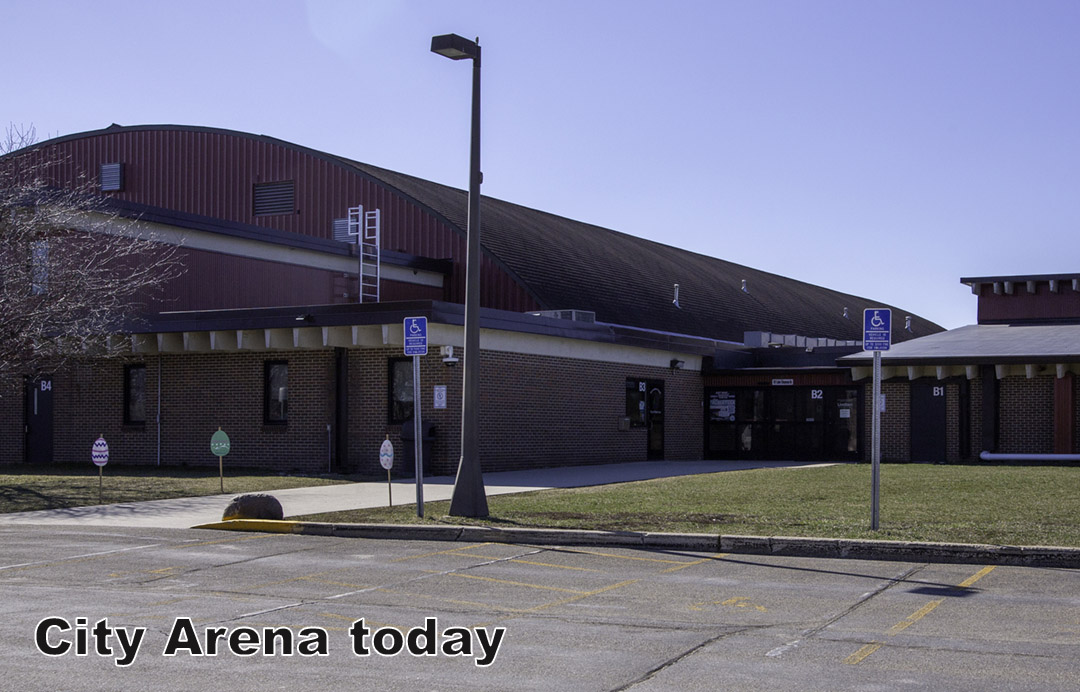 A large brick and metal arena building with accessible parking signs in front; text reads 