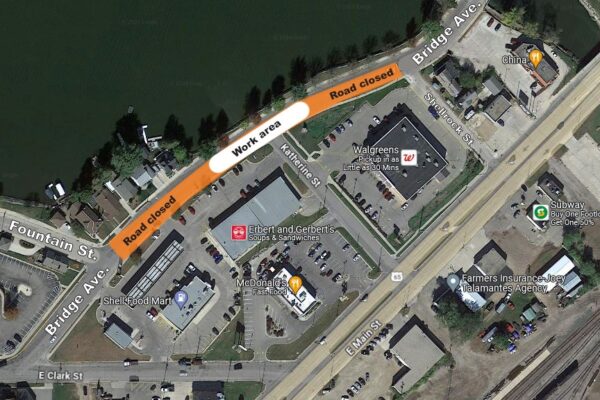 Aerial map view showing a road closure and work area on Bridge Ave near businesses including McDonald's, Walgreens, and China Buffet, next to a river.