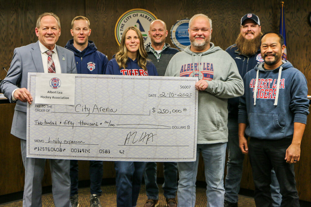Group of people standing and holding a large ceremonial check for $250,000 addressed to City Arena, dated February 10, 2023.