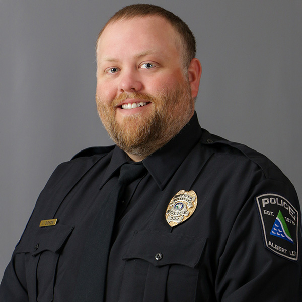 Jacob Gibson, A man in a police uniform smiles against a gray background.