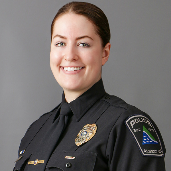Mary Gaul, Smiling police officer in uniform stands against a gray background.