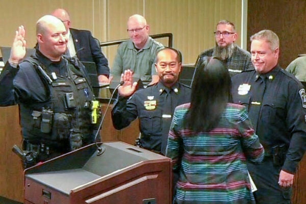 3 police officers take the oath of office at a city council meeting