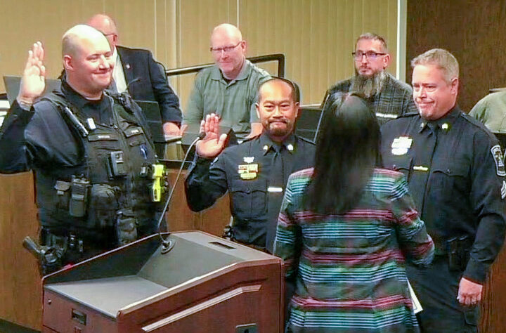 3 police officers take the oath of office at a city council meeting