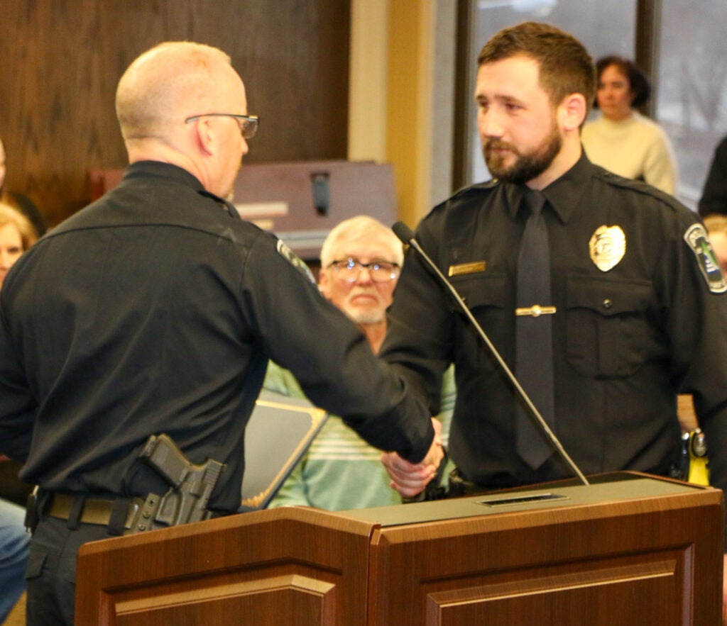 One police officer shakes the hand of another at a meeting