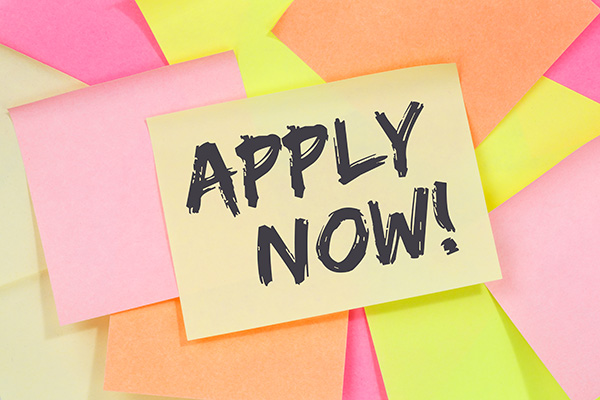 Colorful post its stacked on top of each other, the top post it reads "Apply now"