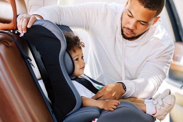 man buckling bay into car seat