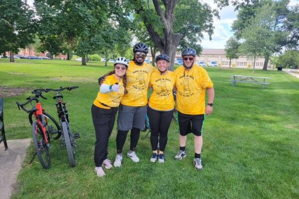 A group of four smiling adults in yellow 