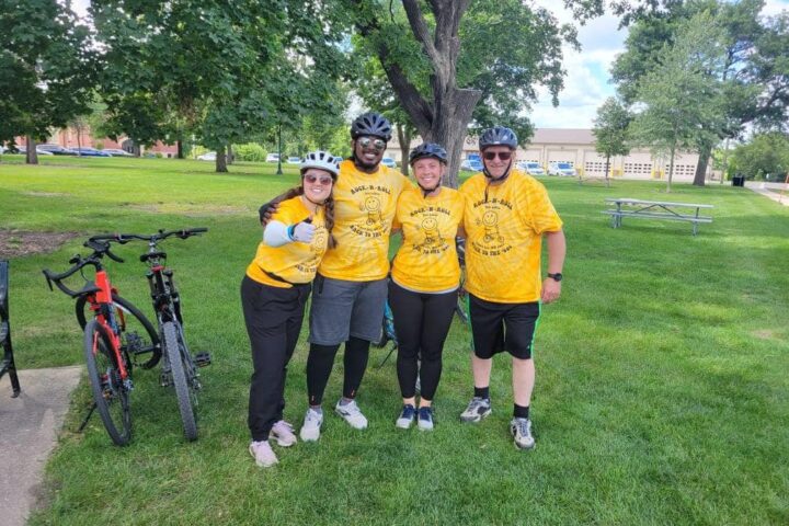 A group of four smiling adults in yellow 