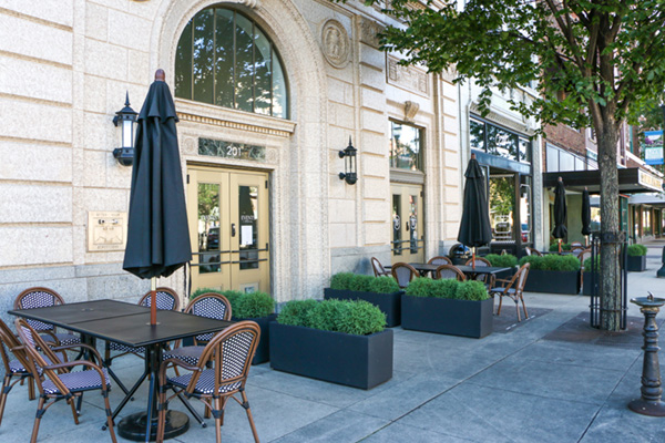 An outdoor patio area in front of a light-colored, ornate building with the address 